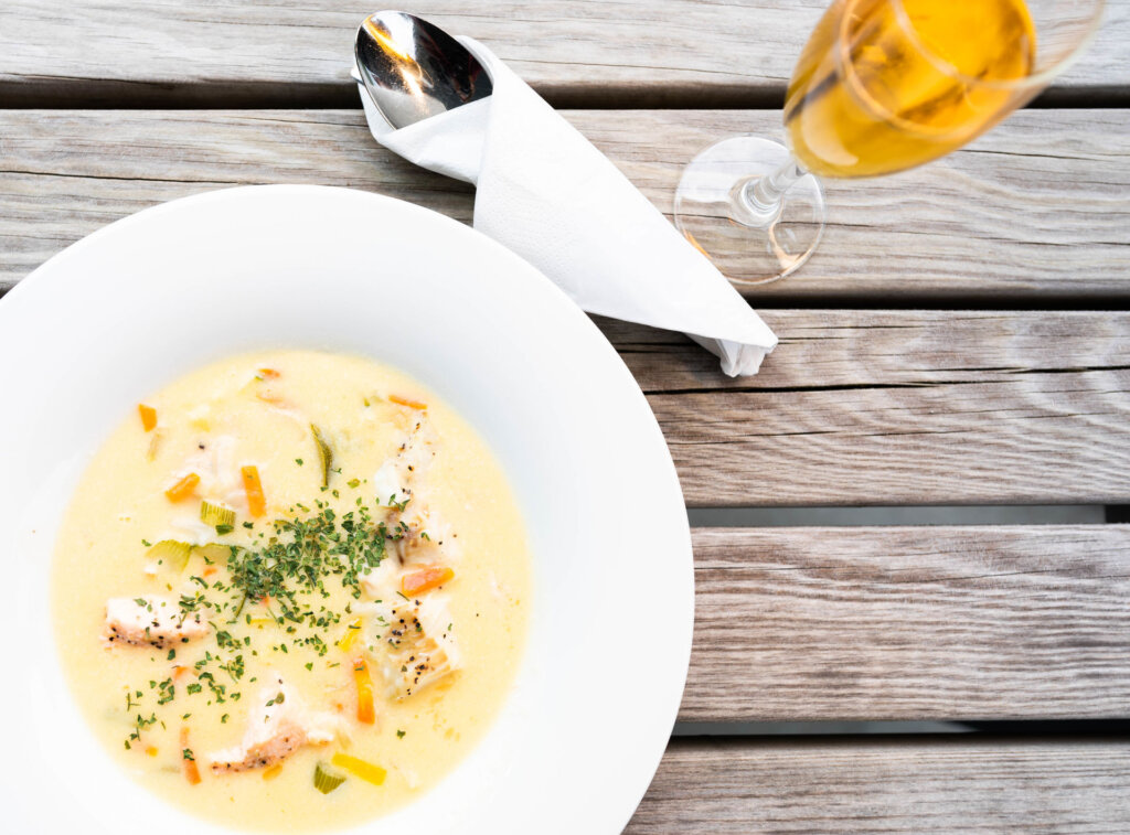 Kremet fiskesuppe og et glass med gyllen drikke på et fjølbord